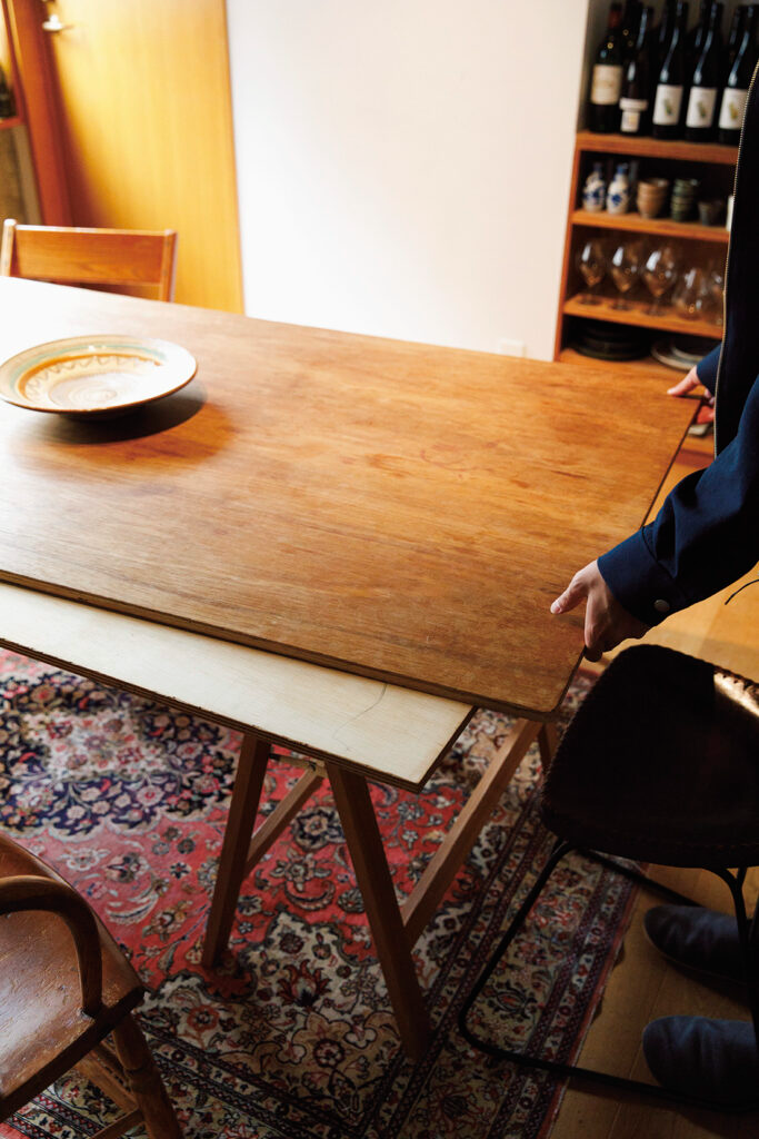 アジアンテイストの濃さを中和するために、 テーブルは合板を 2 枚重ねただけのシンプル なものに。キッチンの収納も、合板のフレー ムに〈無印良品〉の家具を組み合わせた。ど ちらも近所の材木屋で買ってきた材料で自作。